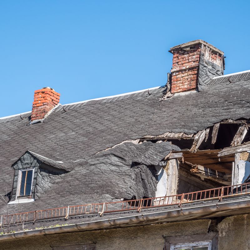 two broken down masonry chimneys on a damaged roof