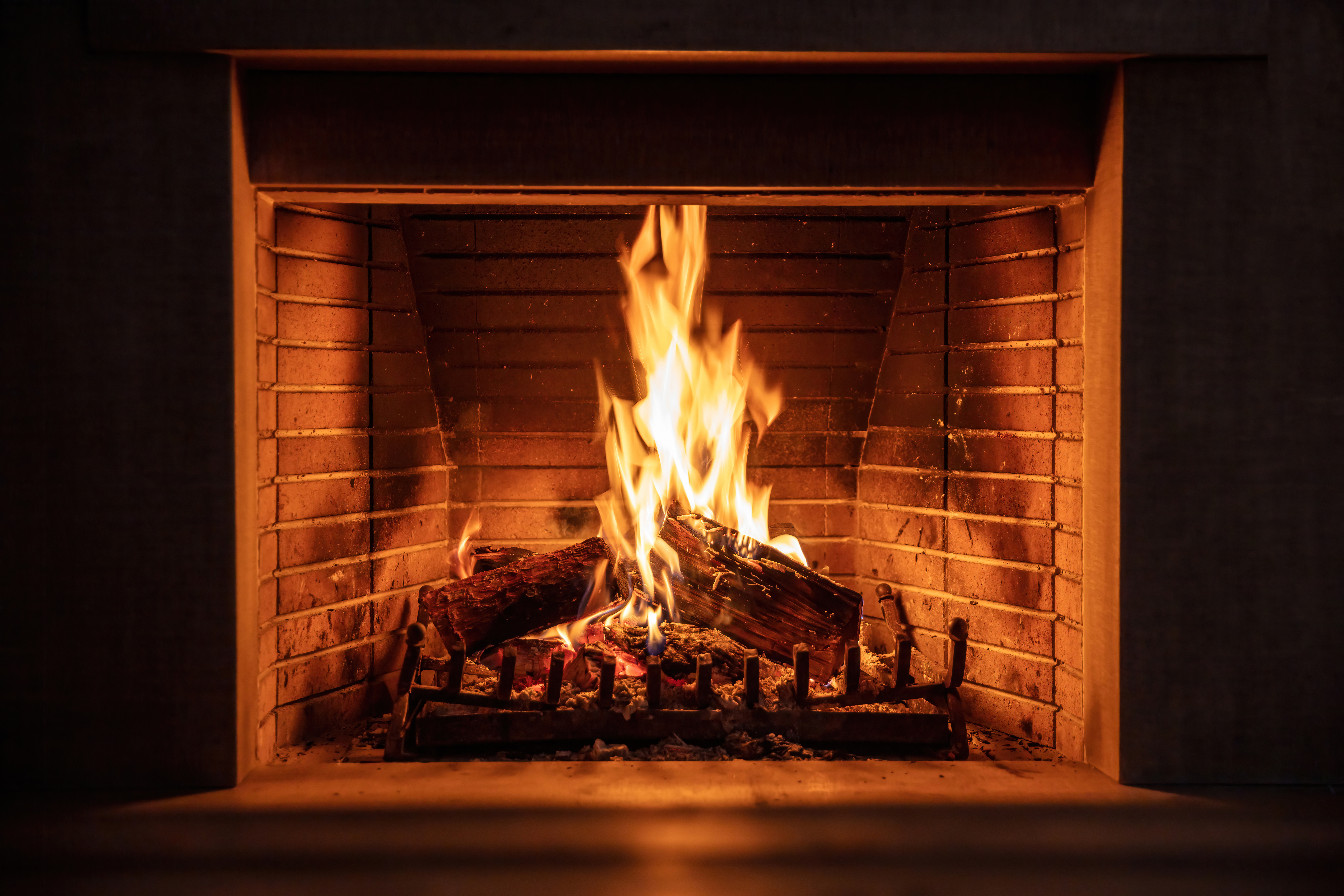 Adobe stock image of wood burning in a masonry fireplace.